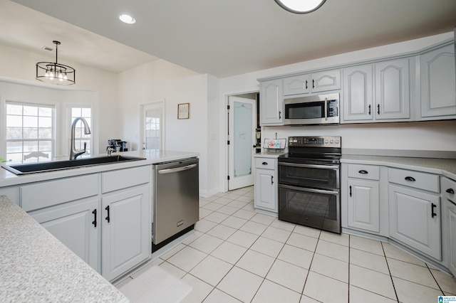 kitchen featuring sink, light tile patterned floors, appliances with stainless steel finishes, decorative light fixtures, and a chandelier