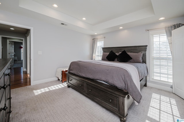 bedroom featuring light colored carpet and a tray ceiling