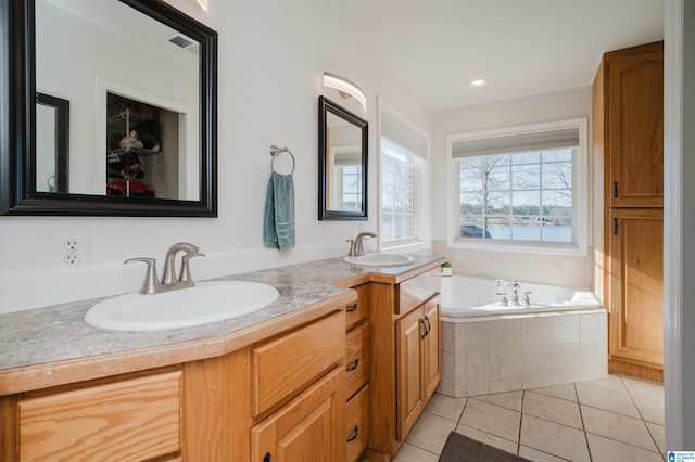 bathroom with tile patterned floors, vanity, and tiled bath