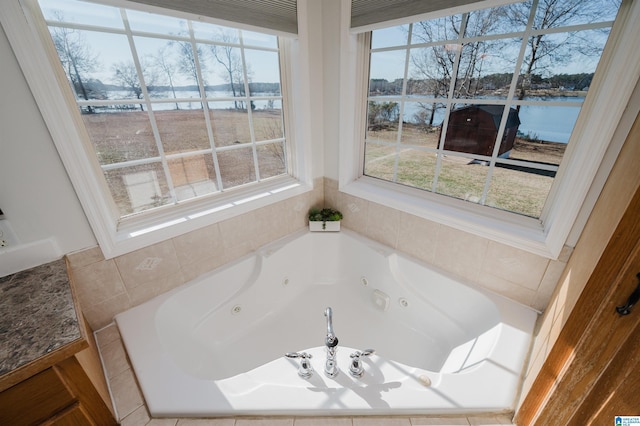 bathroom with tiled tub, a wealth of natural light, and a water view