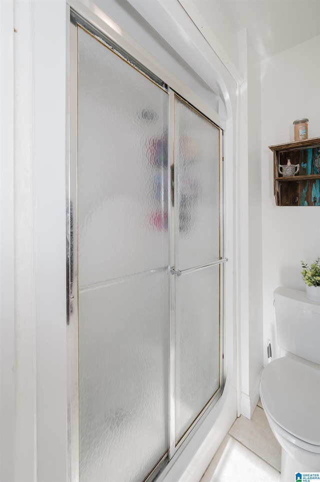 bathroom featuring a shower with shower door and toilet