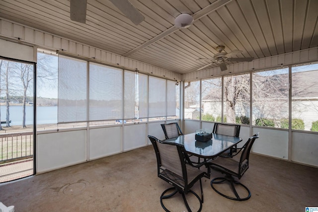 sunroom with ceiling fan and a water view