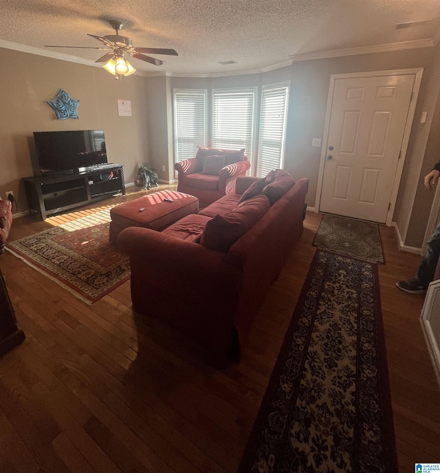 living room featuring a textured ceiling, dark wood-type flooring, ceiling fan, and ornamental molding