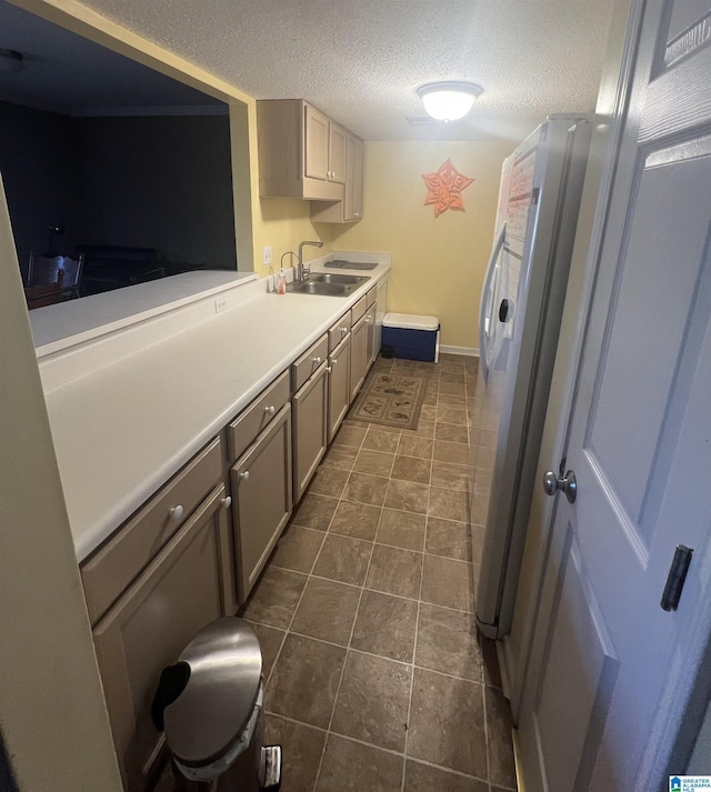 kitchen featuring a textured ceiling, sink, and stainless steel refrigerator