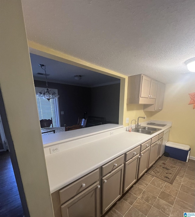 kitchen with gray cabinetry, a textured ceiling, a notable chandelier, and sink