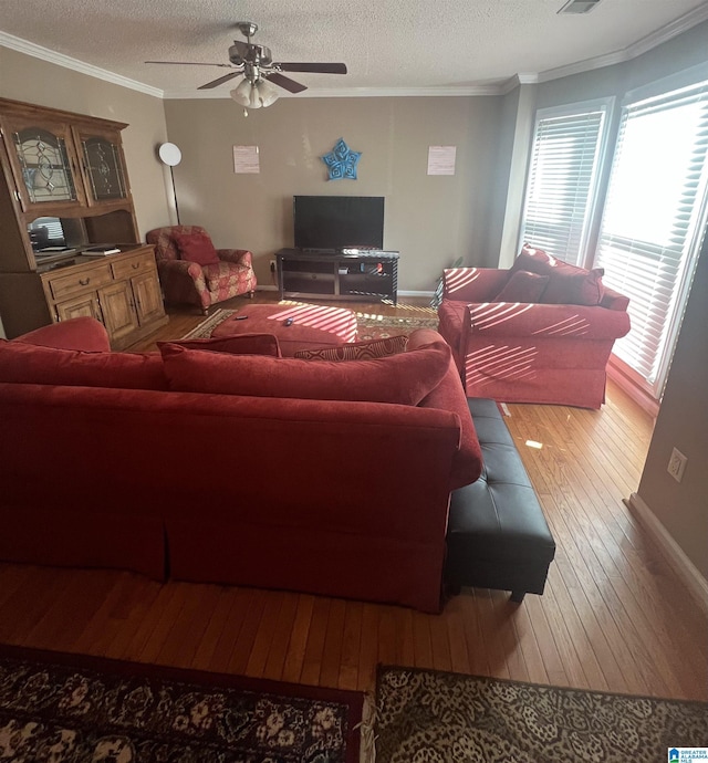 living room featuring hardwood / wood-style flooring, ceiling fan, ornamental molding, and a textured ceiling