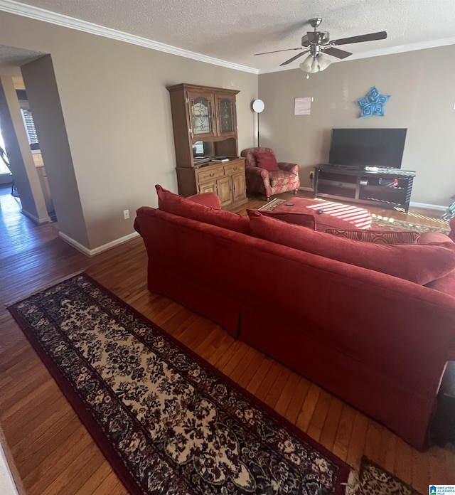 living room with ceiling fan, crown molding, dark wood-type flooring, and a textured ceiling