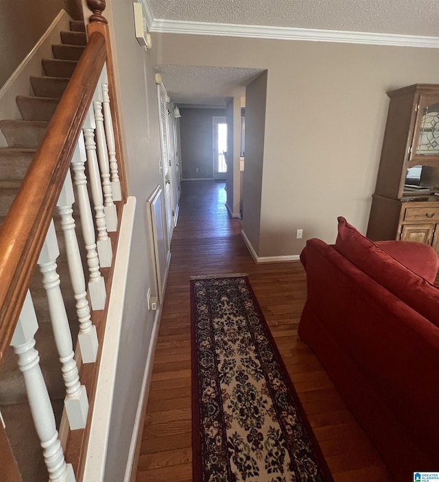 corridor with dark hardwood / wood-style floors, a textured ceiling, and ornamental molding