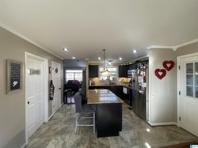 kitchen featuring a center island, a kitchen breakfast bar, light stone counters, stainless steel fridge, and crown molding