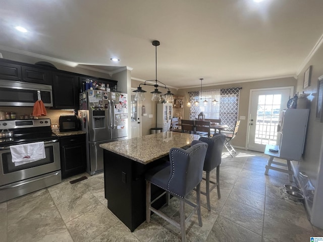 kitchen with light stone counters, stainless steel appliances, a kitchen island, hanging light fixtures, and a breakfast bar area