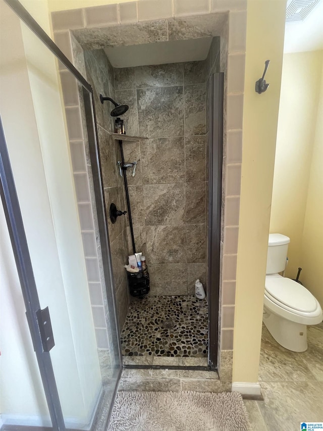 bathroom featuring toilet and a shower with shower door