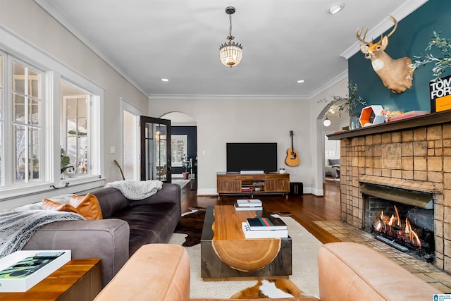 living room with wood-type flooring, a brick fireplace, and ornamental molding