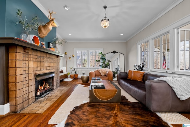 living room featuring hardwood / wood-style floors, crown molding, and a brick fireplace