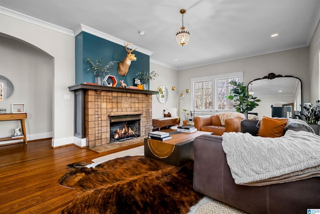 living room featuring crown molding, a fireplace, and wood-type flooring