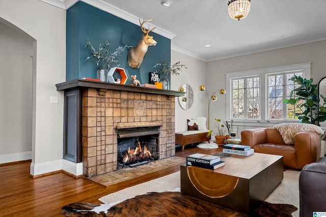 living room with a fireplace, wood-type flooring, and ornamental molding