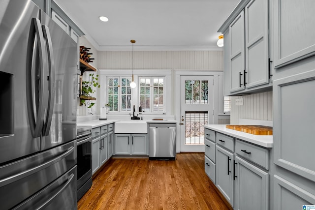 kitchen featuring stainless steel appliances, sink, decorative light fixtures, hardwood / wood-style floors, and gray cabinets