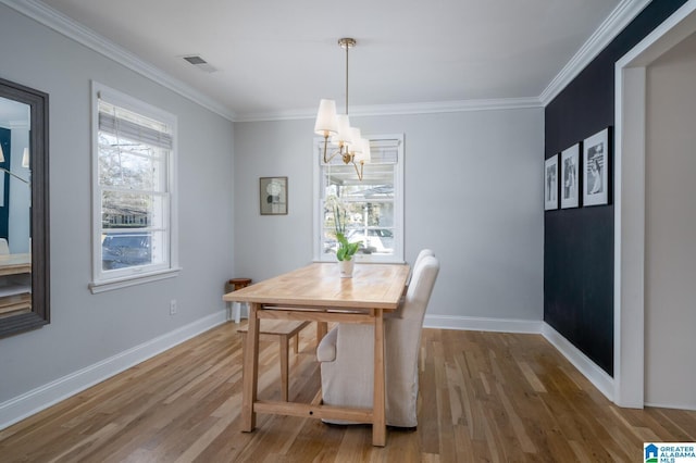 dining space with crown molding, wood-type flooring, and an inviting chandelier