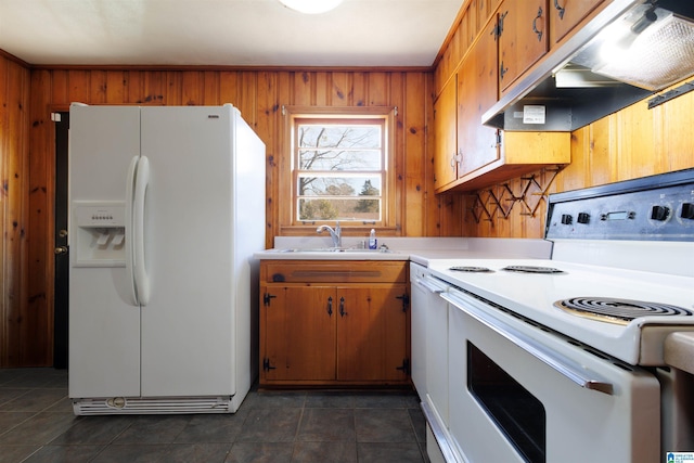 kitchen with wood walls, white appliances, sink, and dark tile patterned floors