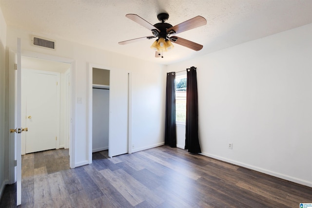 unfurnished bedroom with ceiling fan, dark hardwood / wood-style flooring, and a textured ceiling