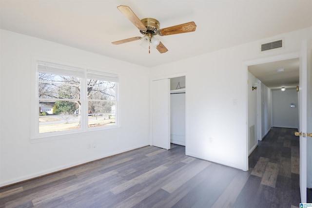 unfurnished bedroom with a closet, dark hardwood / wood-style floors, and ceiling fan