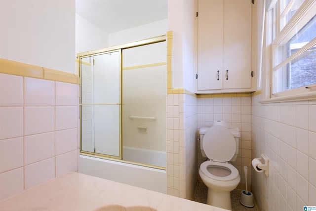 full bathroom with shower / bath combination with glass door, vanity, tile walls, and toilet