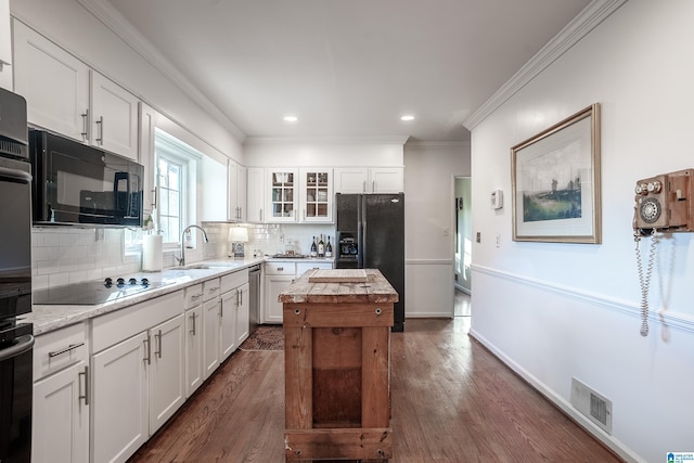 kitchen with sink, dark hardwood / wood-style floors, backsplash, white cabinets, and black appliances