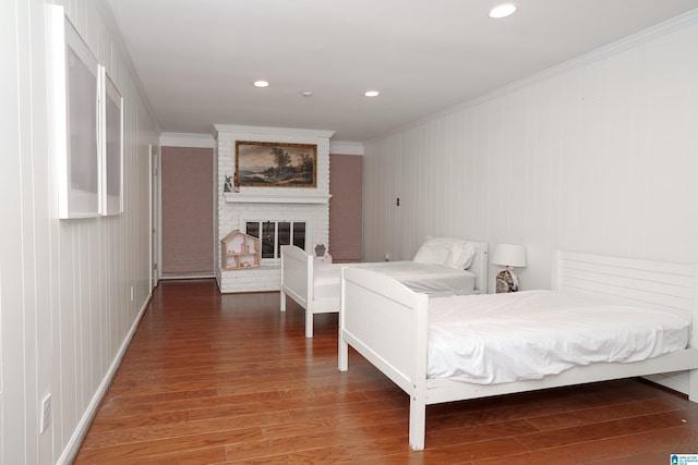 bedroom with wood-type flooring, a brick fireplace, and ornamental molding