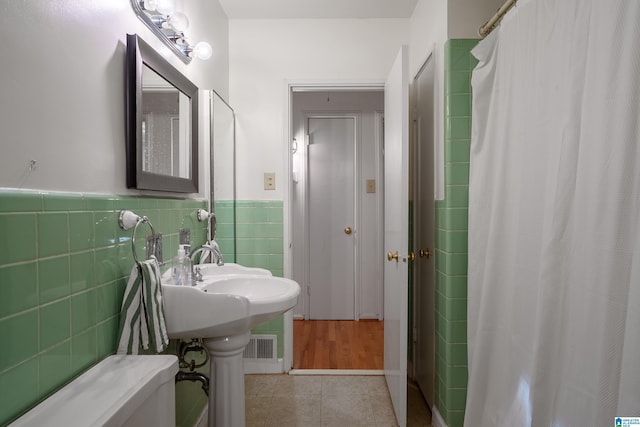 bathroom featuring tile patterned flooring, tile walls, and walk in shower