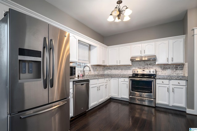 kitchen with white cabinetry, stainless steel appliances, tasteful backsplash, dark stone countertops, and a chandelier