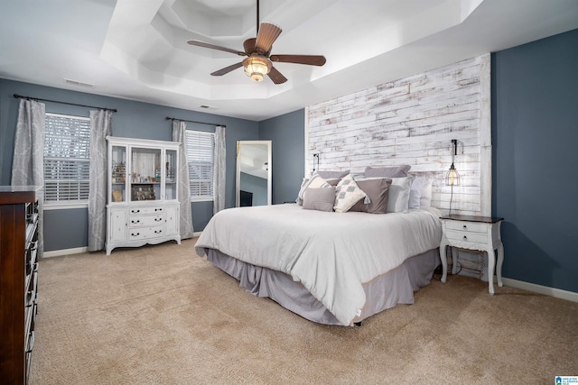 bedroom featuring ceiling fan, light carpet, and a tray ceiling