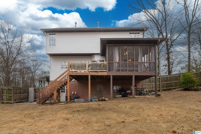 rear view of property with a sunroom, a yard, and a deck