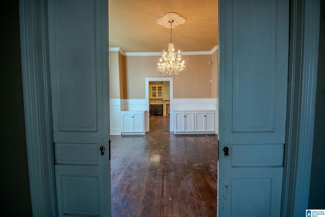 hallway featuring dark hardwood / wood-style floors, crown molding, and a chandelier