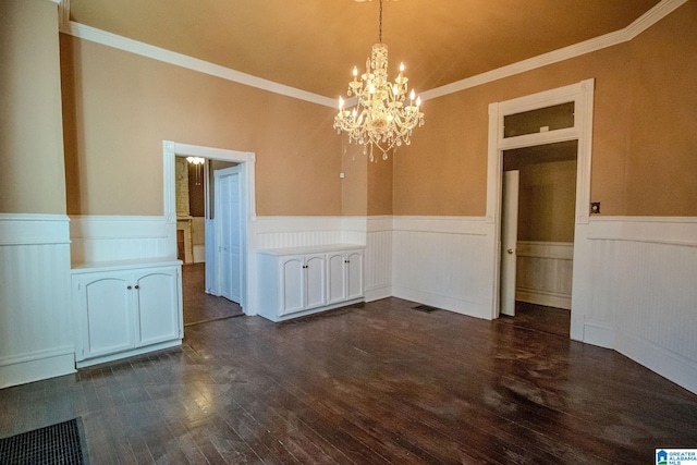 unfurnished dining area featuring dark hardwood / wood-style floors, crown molding, and a chandelier