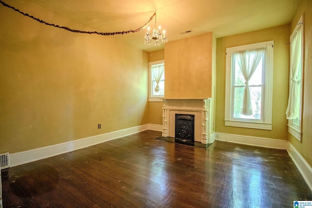 unfurnished living room with baseboards, visible vents, a notable chandelier, hardwood / wood-style flooring, and a fireplace