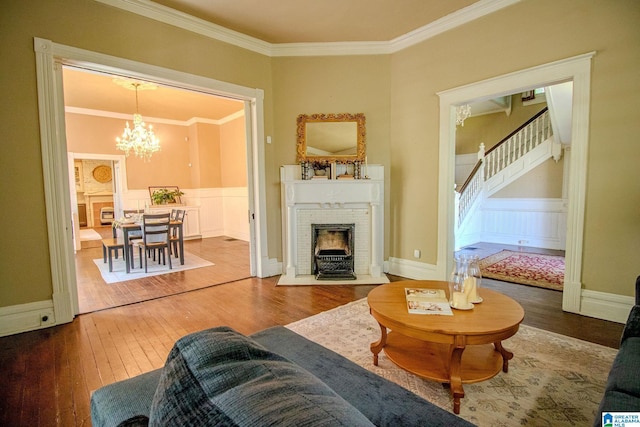 living room with crown molding, an inviting chandelier, stairway, and wood-type flooring