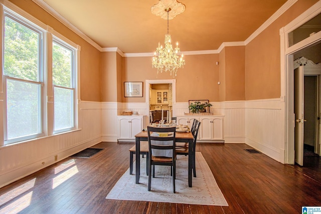 dining room with a wainscoted wall, visible vents, ornamental molding, dark wood-type flooring, and a notable chandelier