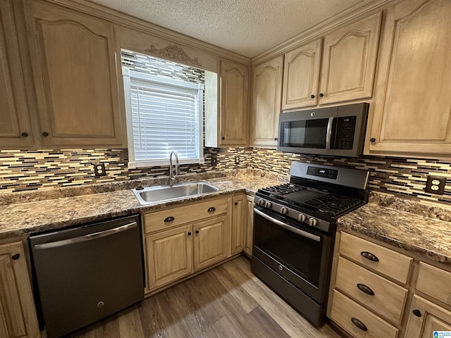 kitchen featuring light brown cabinetry, sink, appliances with stainless steel finishes, and dark stone counters