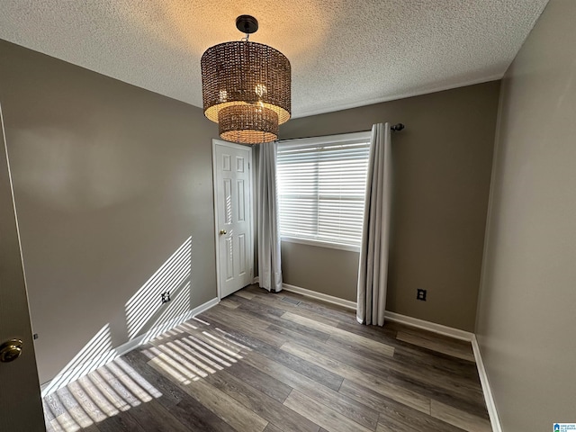 unfurnished room featuring hardwood / wood-style flooring, a textured ceiling, and a notable chandelier