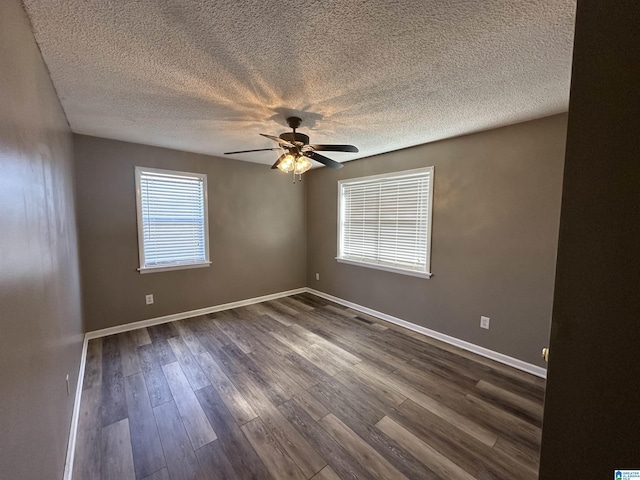 empty room featuring a wealth of natural light, dark hardwood / wood-style flooring, ceiling fan, and a textured ceiling