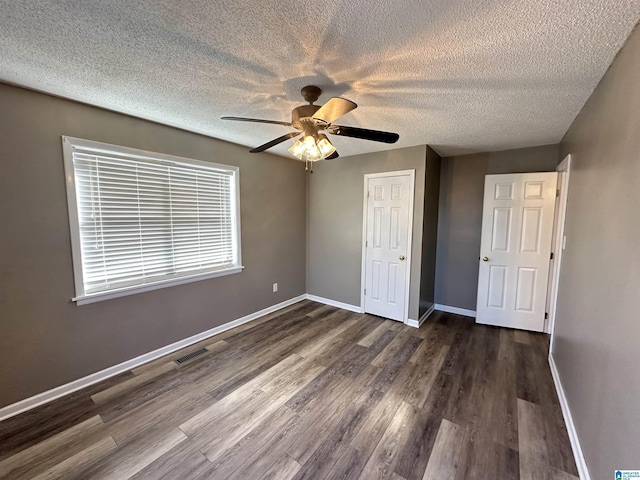 unfurnished bedroom with ceiling fan, a closet, and dark wood-type flooring