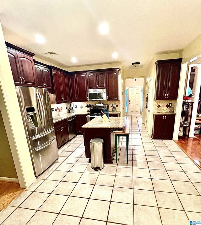 kitchen with a kitchen breakfast bar, a center island, light tile patterned floors, and appliances with stainless steel finishes