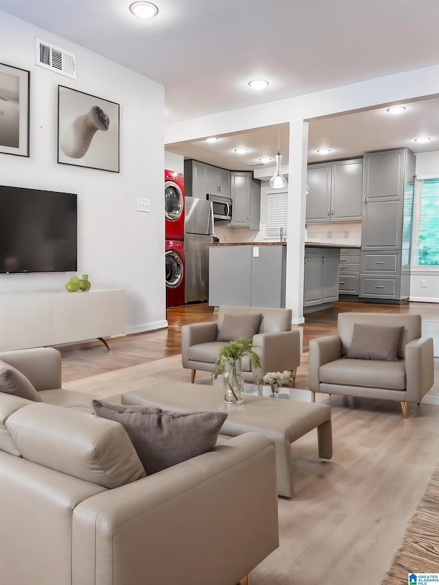 living room featuring light wood-type flooring and stacked washer / dryer