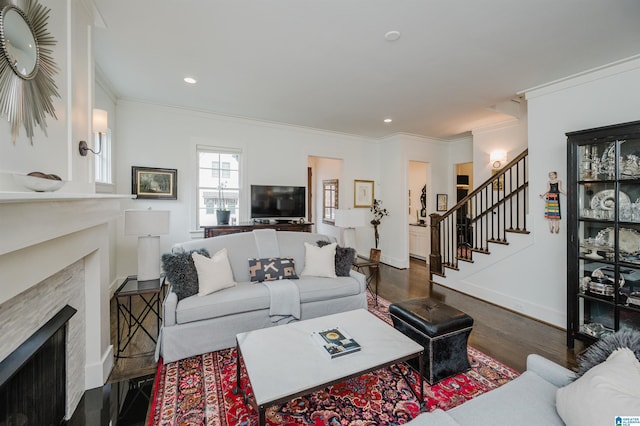 living room with a high end fireplace, dark hardwood / wood-style flooring, and ornamental molding