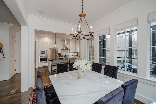 dining area with dark hardwood / wood-style floors, an inviting chandelier, a wealth of natural light, and crown molding