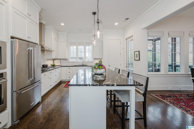 kitchen featuring a breakfast bar, a center island, dark hardwood / wood-style floors, white cabinetry, and stainless steel appliances