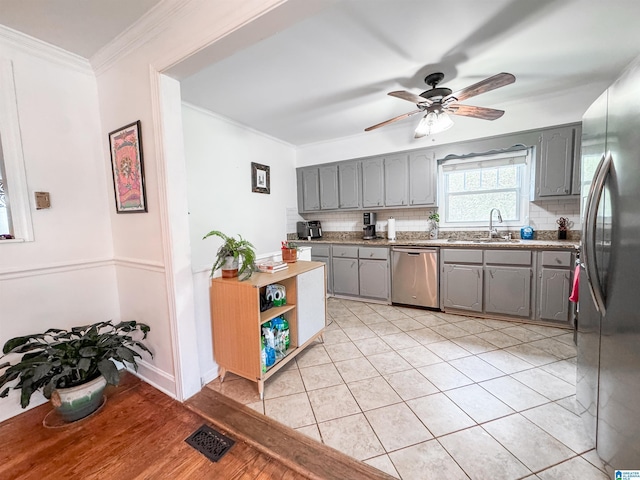 kitchen with tasteful backsplash, gray cabinets, sink, and appliances with stainless steel finishes