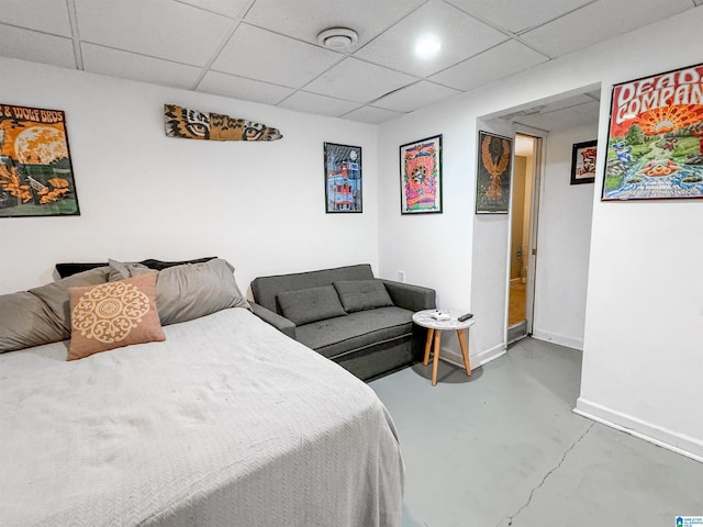 bedroom with concrete floors and a paneled ceiling