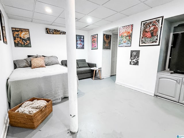 bedroom with concrete floors and a drop ceiling