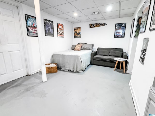 bedroom with a paneled ceiling and concrete flooring