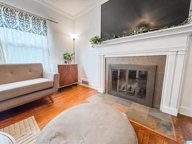 living area featuring hardwood / wood-style flooring, crown molding, and a fireplace